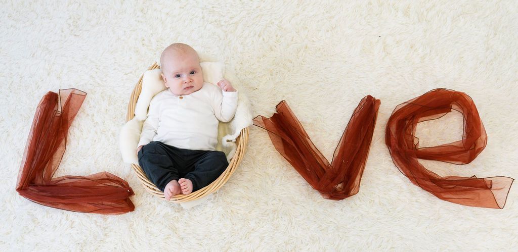 A baby is laying in a basket with the word love written on the floor