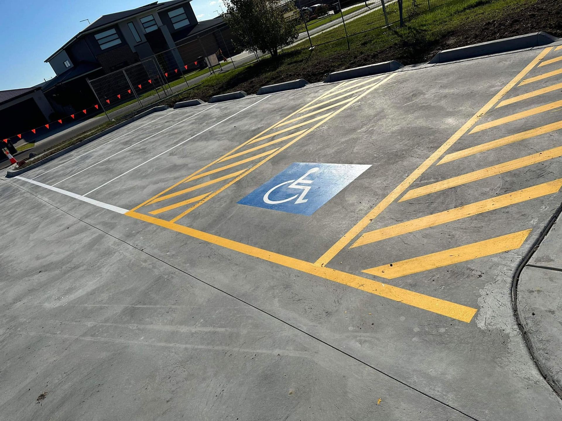 Handicapped parking space marked with blue wheelchair symbol and yellow diagonal lines on concrete lot