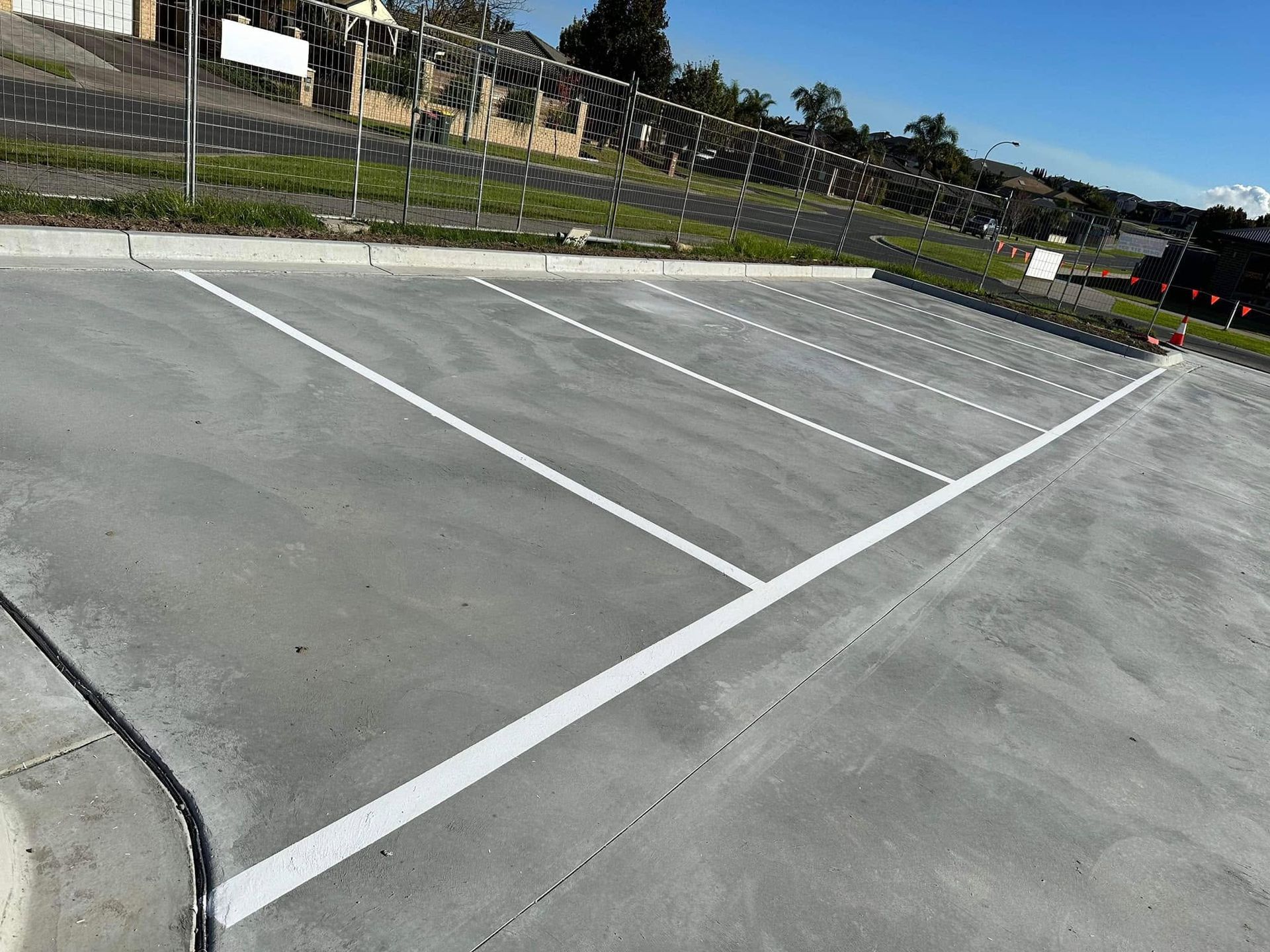 Empty outdoor parking lot with white painted lines on gray pavement, viewed at an angle.