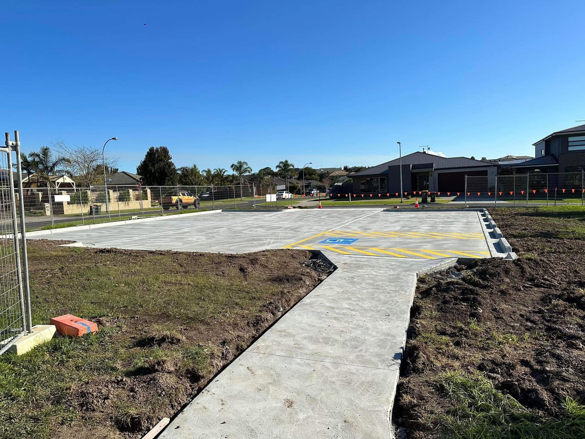 Concrete path leading to a large paved area in an open field under a clear blue sky