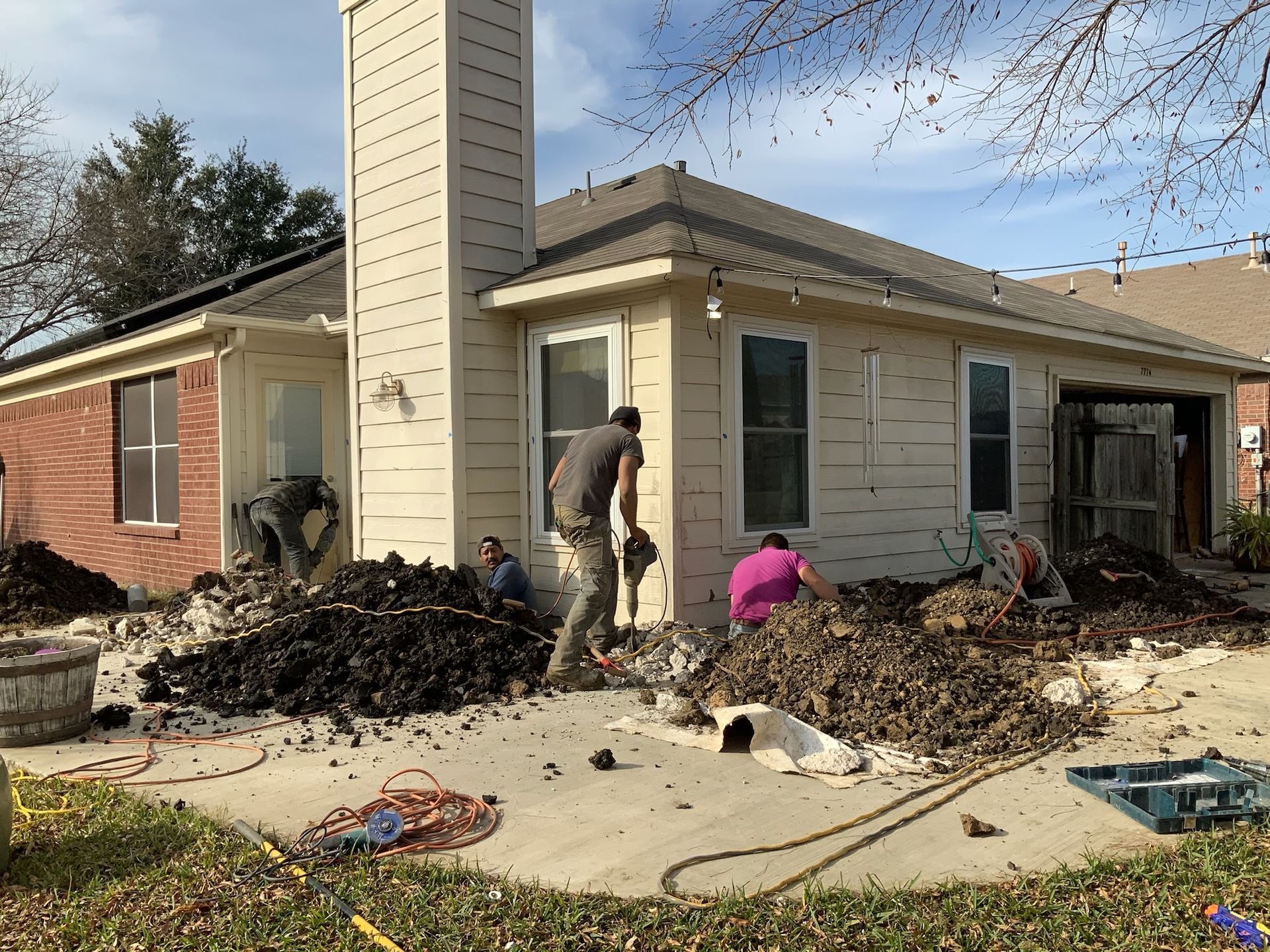 a group of men are digging in front of a house