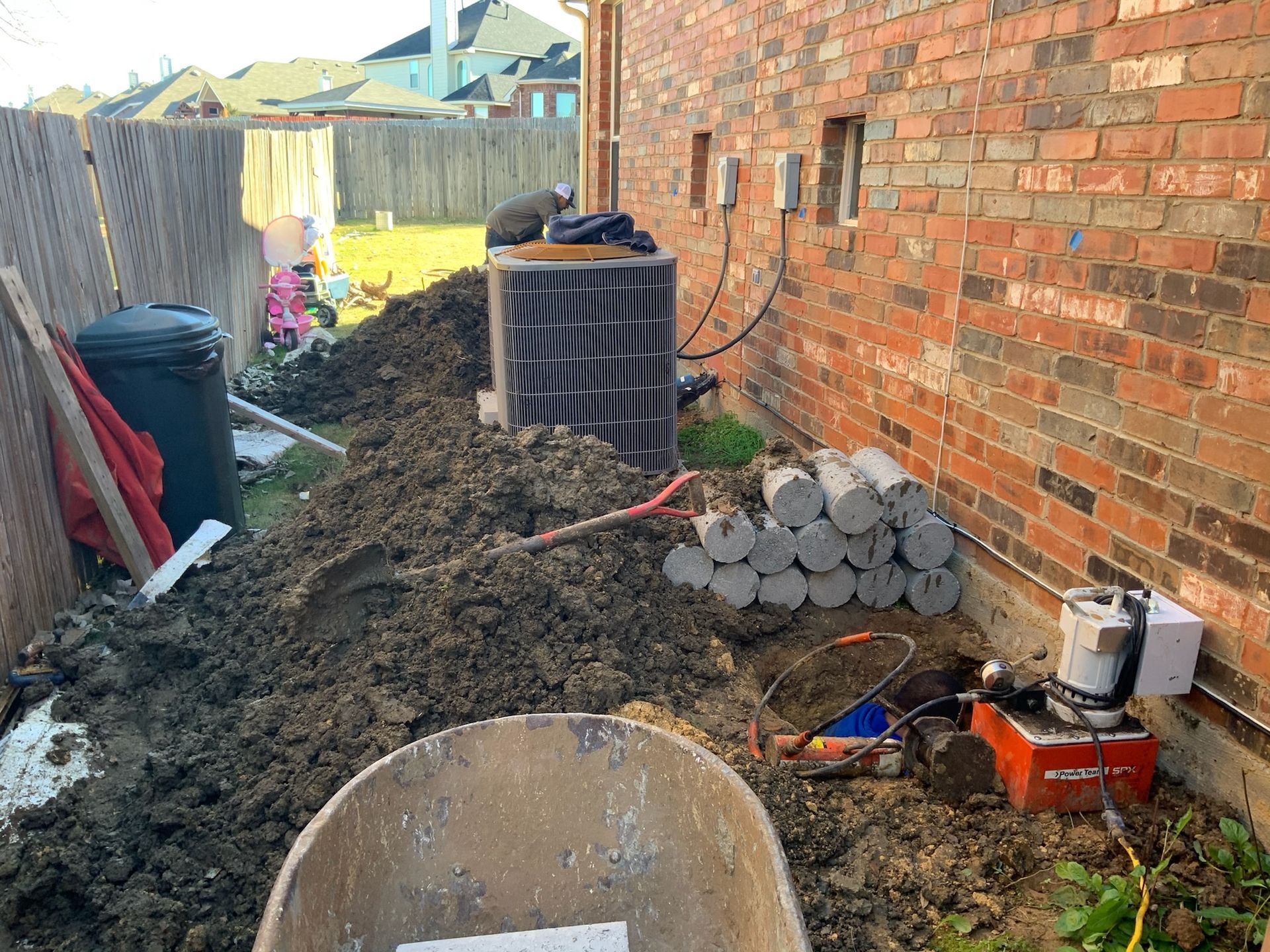 a wheelbarrow sits in the dirt in front of a brick wall