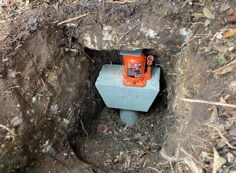 a bottle jack is sitting on top of a concrete block in the dirt
