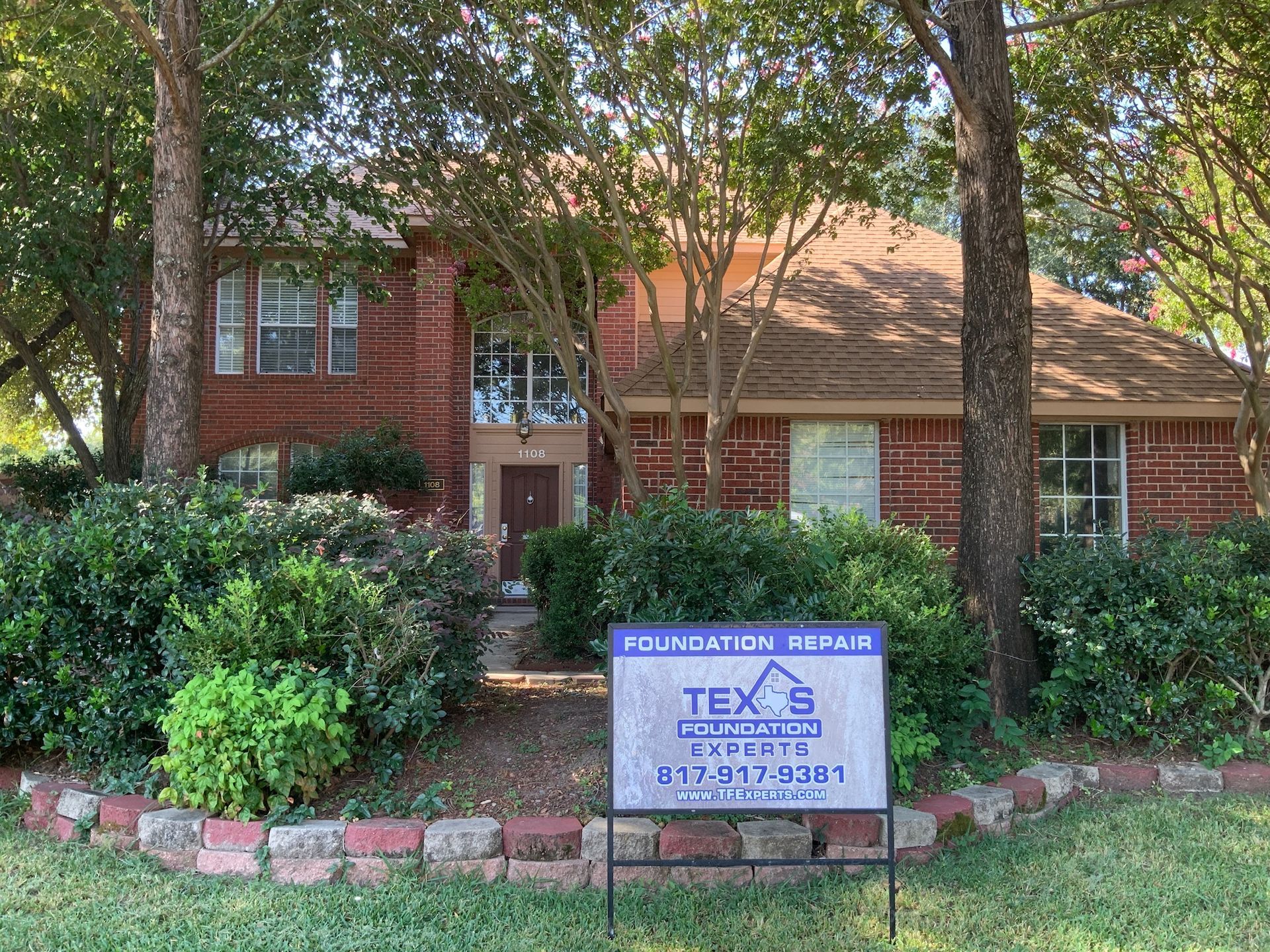 a texas foundation repair sign in front of a brick house