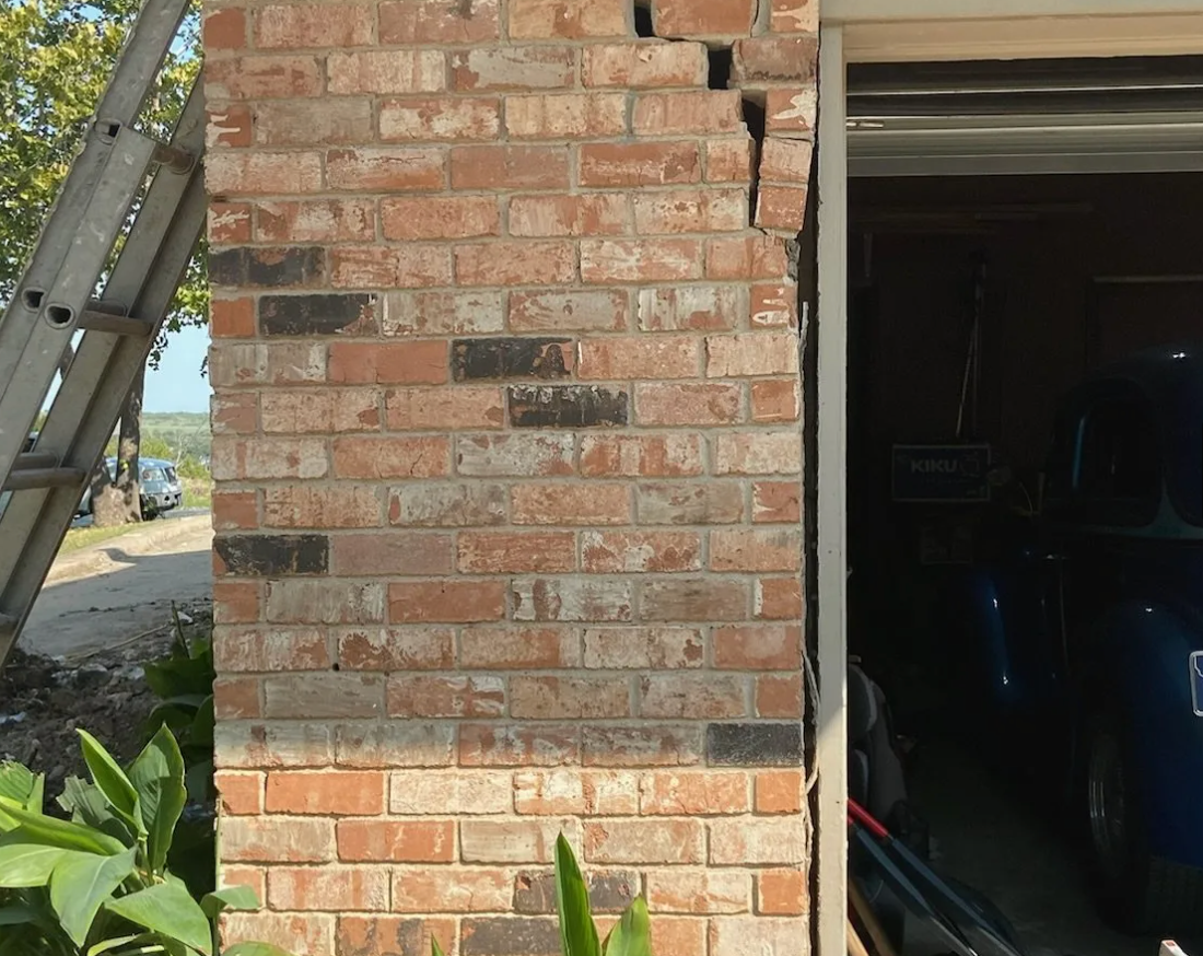 a brick wall next to a garage with a sign that says ' yowie ' on it