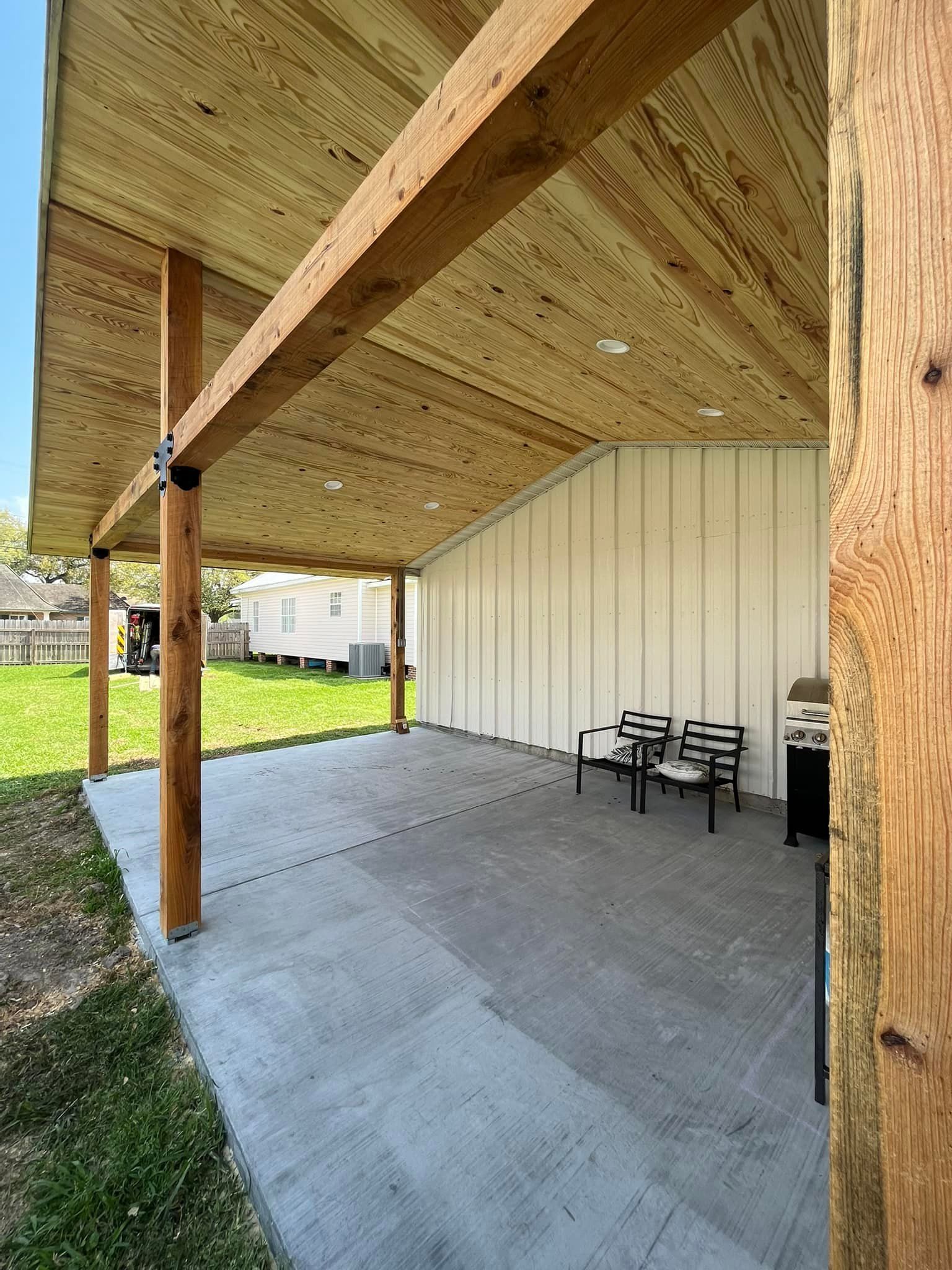 A covered patio with a wooden roof and a concrete floor.