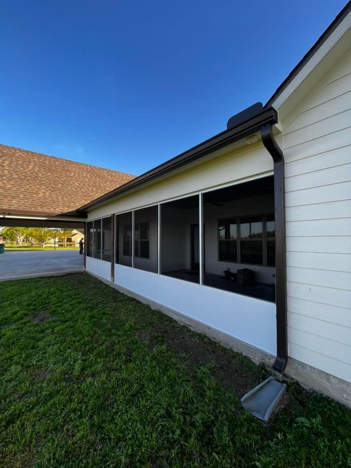 A white house with a screened in porch and a brown gutter