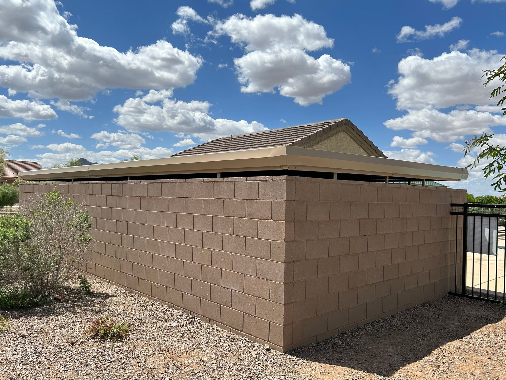 A brick building with a roof and a fence in front of it.