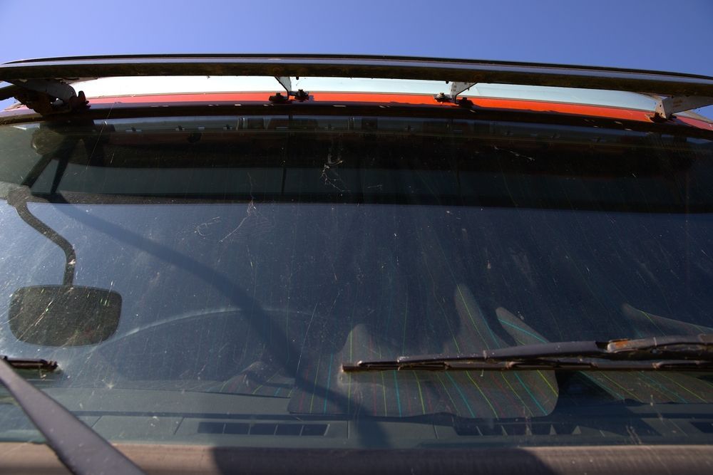 Close-up of a Dirty Windshield of a Red Vehicle With Visible Wiper Blades — Road Runner Windscreens in Maclean, NSW
