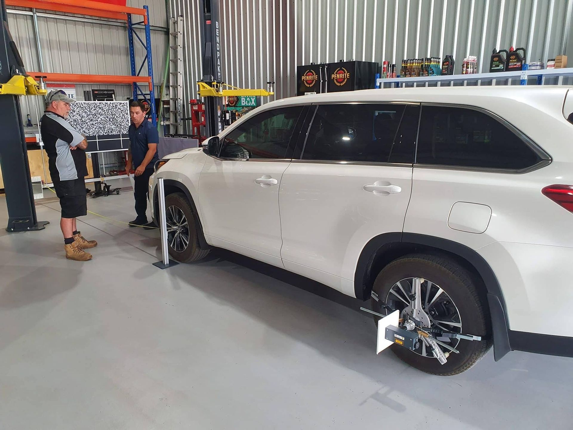 Two Mechanics Aligning a White Suv's Wheels in a Garage — Road Runner Windscreens in South Grafton, NSW