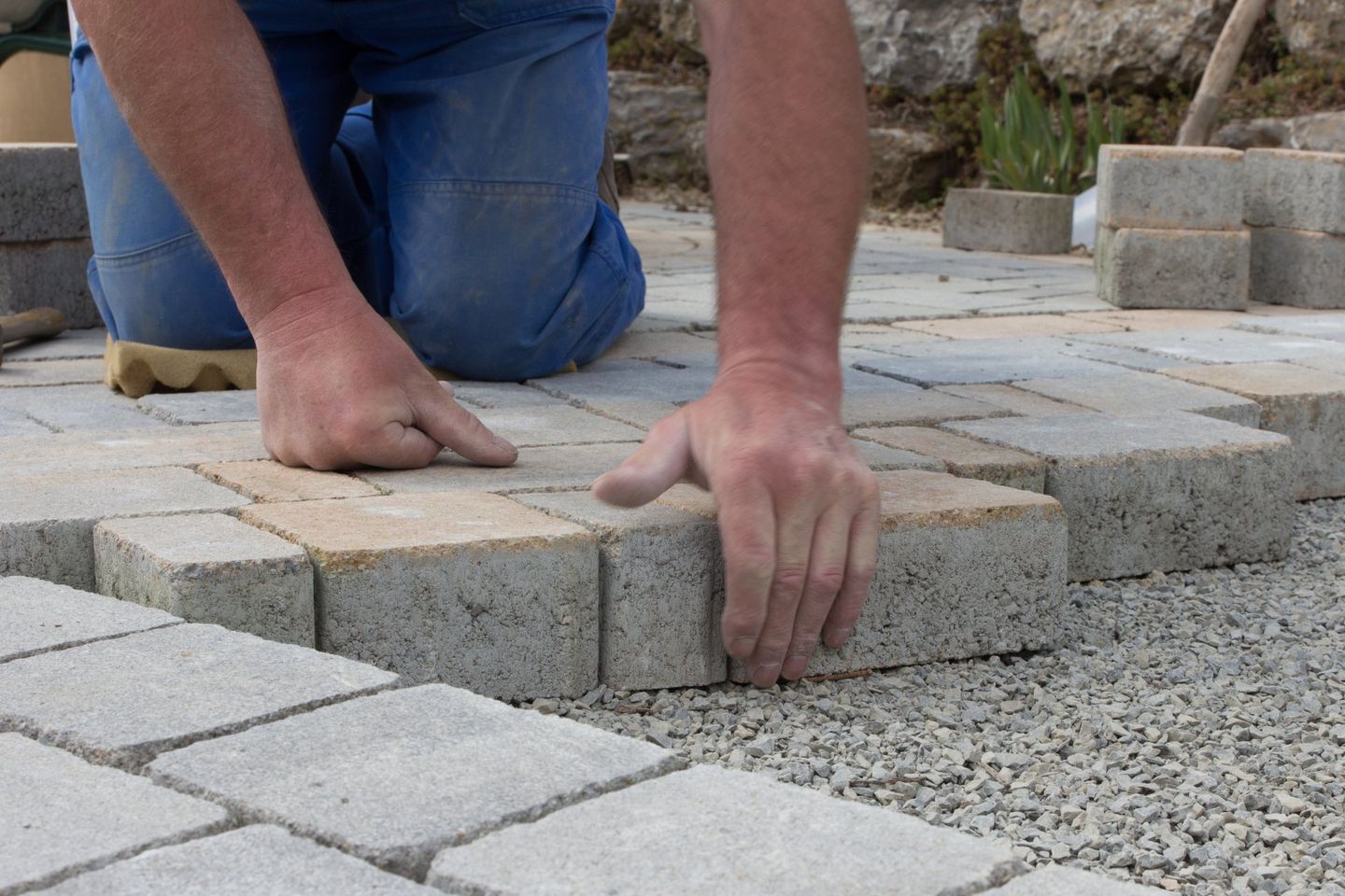 masonry contractor laying stone bricks to build stone patio