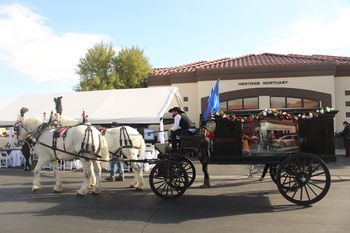 A horse drawn carriage is pulled by two white horses.