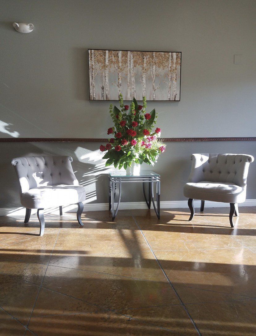 A room with two chairs and a vase of flowers on a table