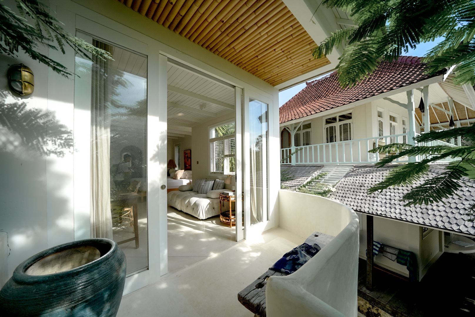 Balcony overlooking a white house with a red tiled roof. The balcony has a curved white railing.
