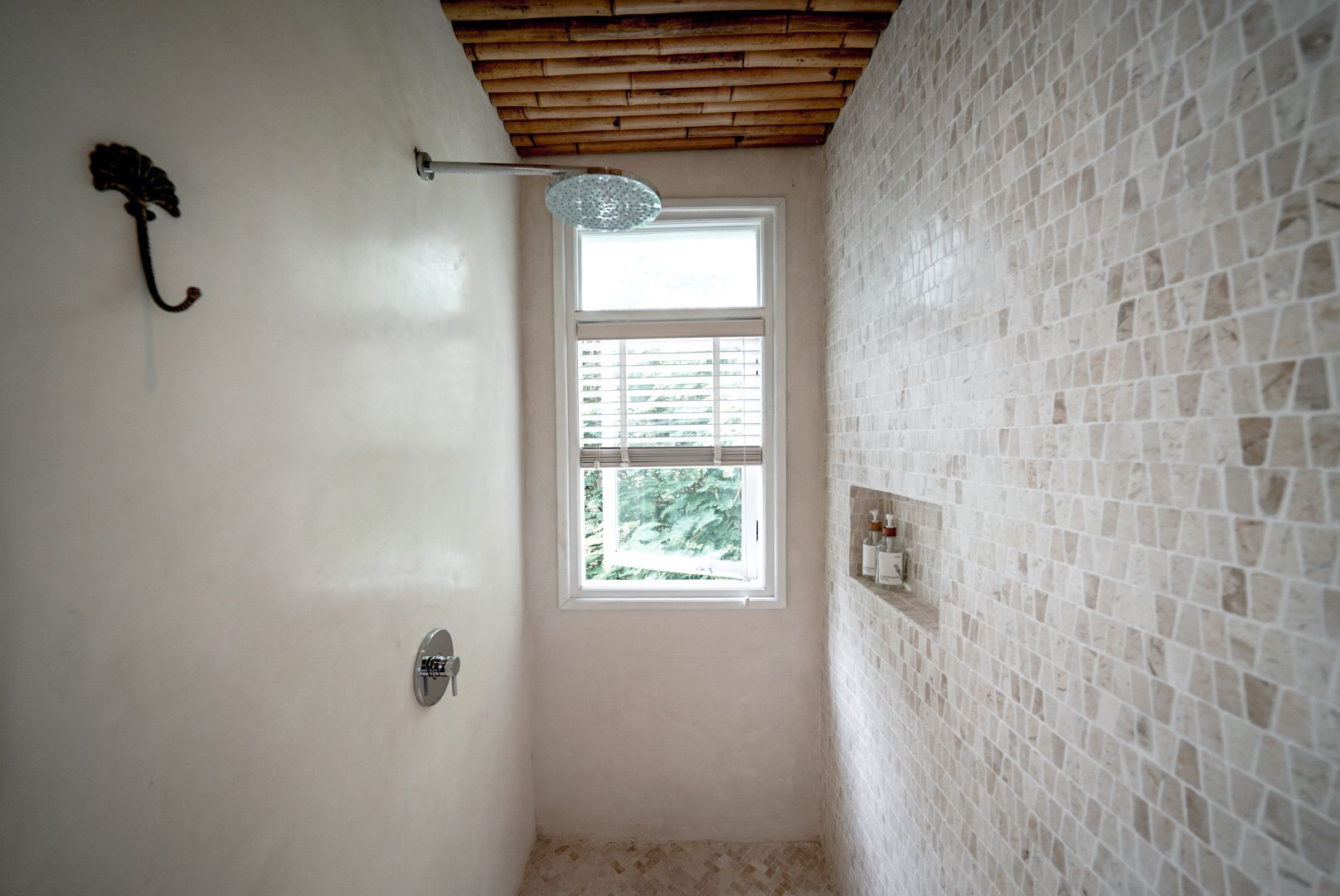 Shower with white walls, mosaic tile, a window, and a bamboo ceiling. An umbrella hook is on the left wall.