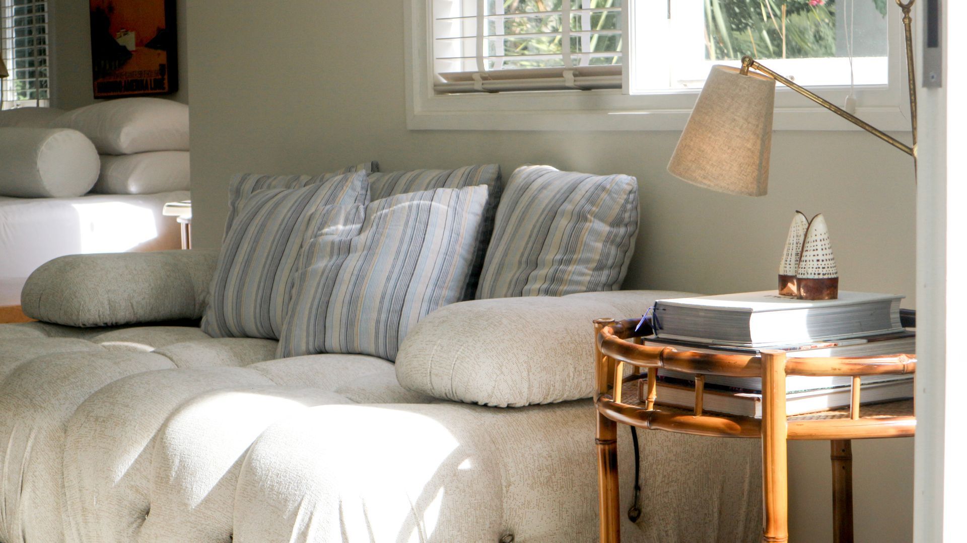 Cozy room with a daybed, pillows, side table with lamp, and a window with natural light.