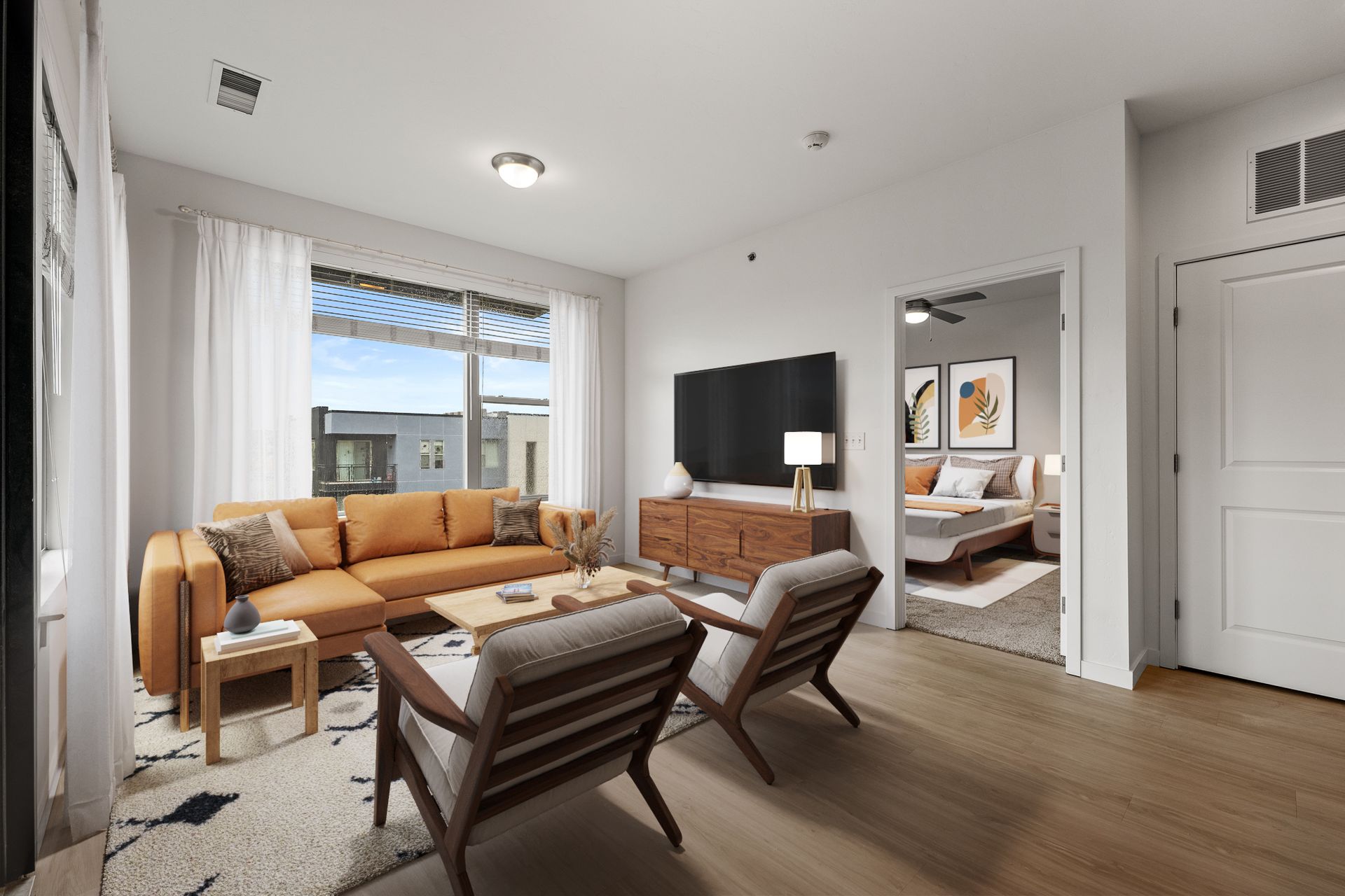 Living room in an apartment with a mustard sofa, two wooden lounge chairs, a TV, and a doorway to the bedroom.