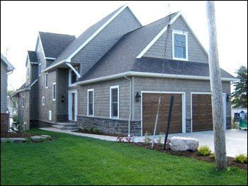 A large house with two garage doors and a large lawn in front of it