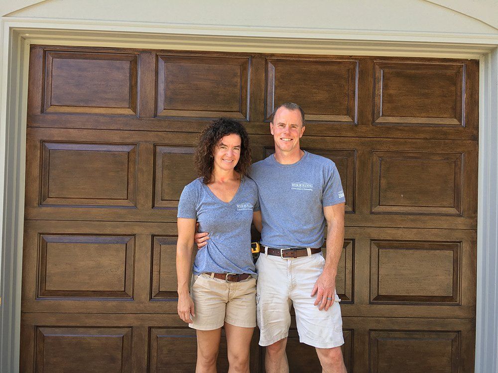 A man and a woman are standing in front of a garage door.