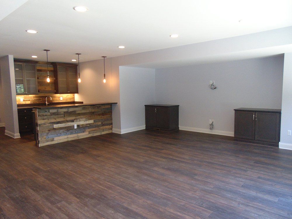 A large empty room with hardwood floors and a wooden bar.