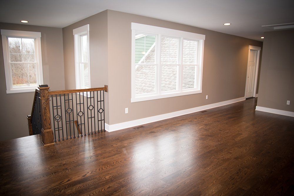 An empty living room with hardwood floors and a large window.