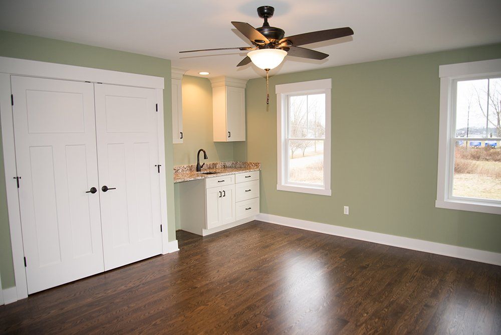 An empty room with green walls and a ceiling fan