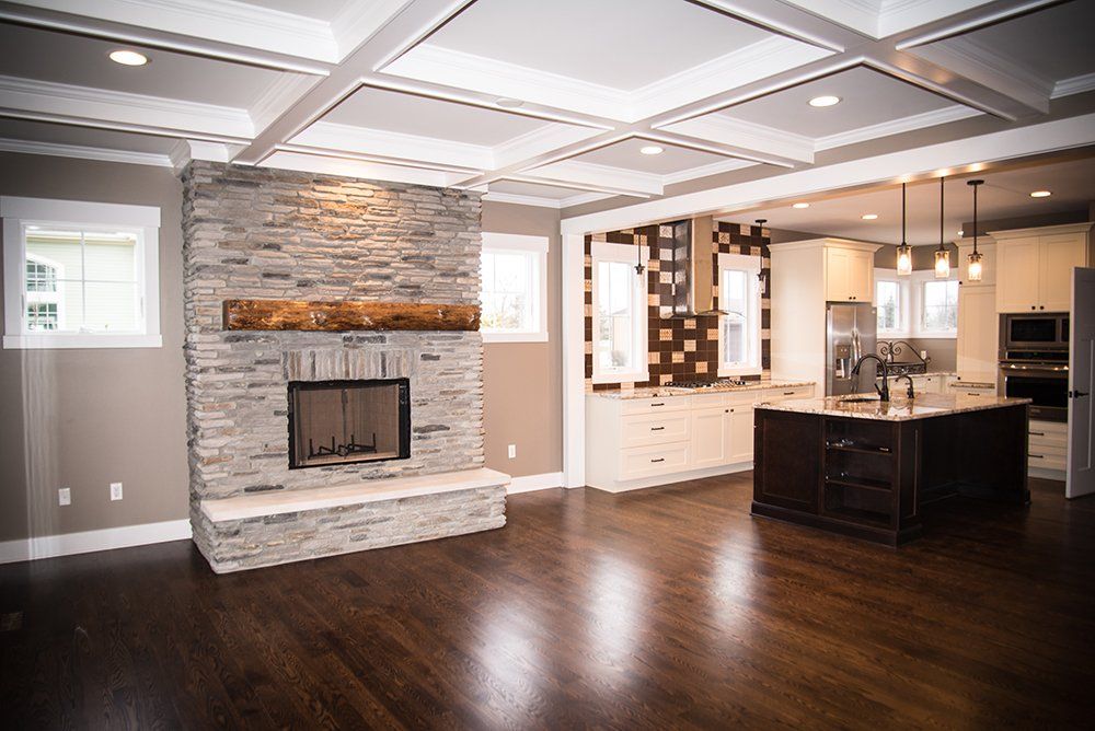 A living room with a fireplace and a kitchen in the background.