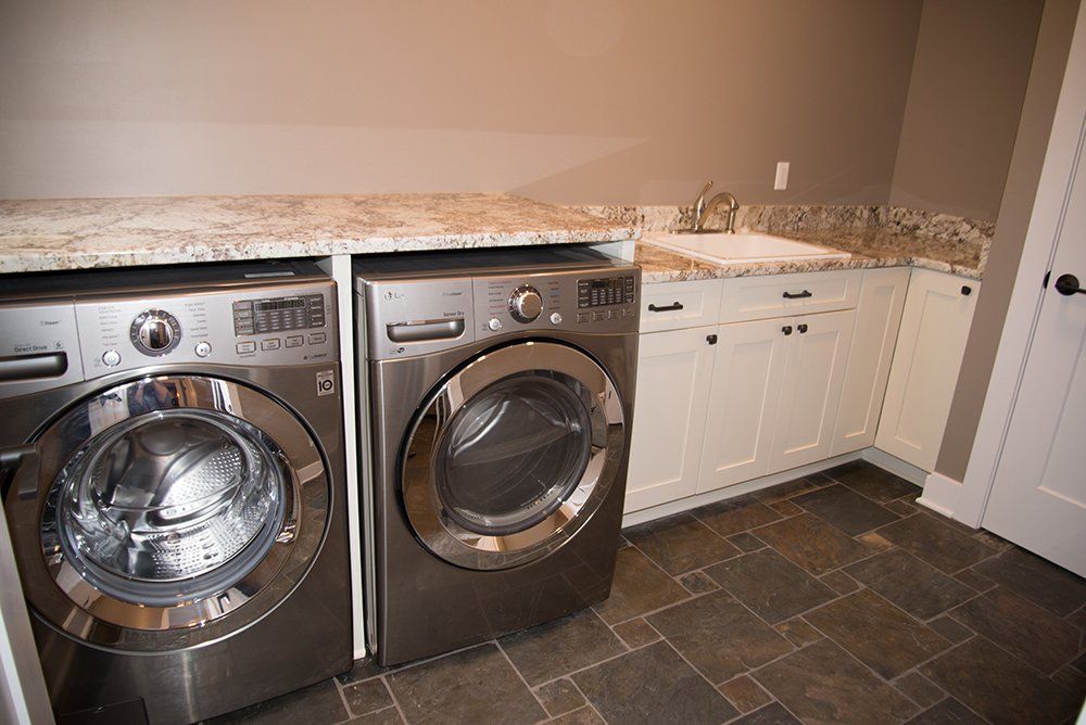 A laundry room with a washer and dryer and a sink.