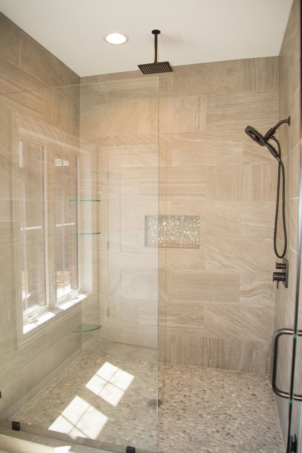 A walk in shower with a glass door and a shower head.