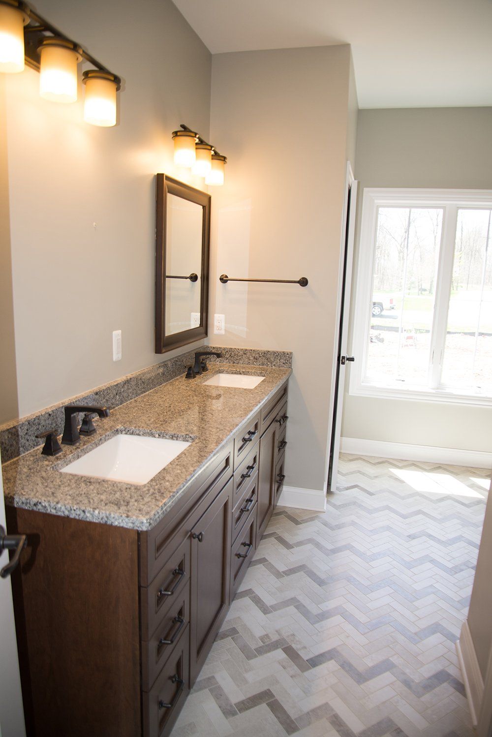 A bathroom with two sinks , a mirror and a window.