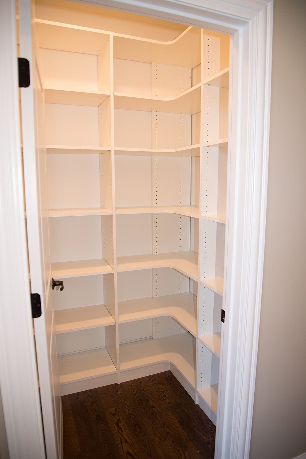 A pantry with lots of shelves and a door.