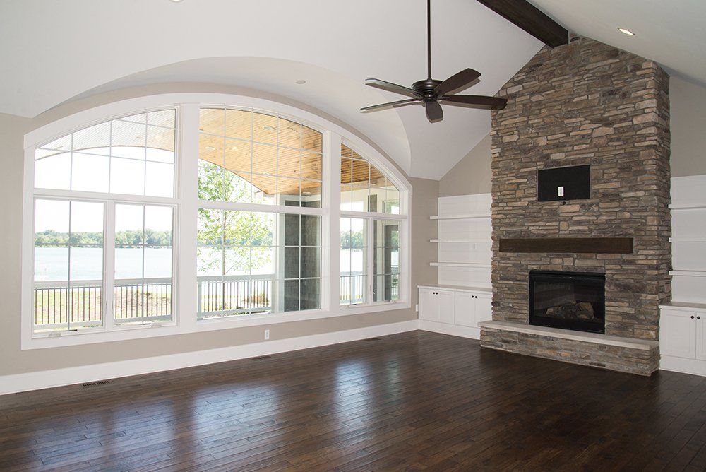 An empty living room with a fireplace and a ceiling fan