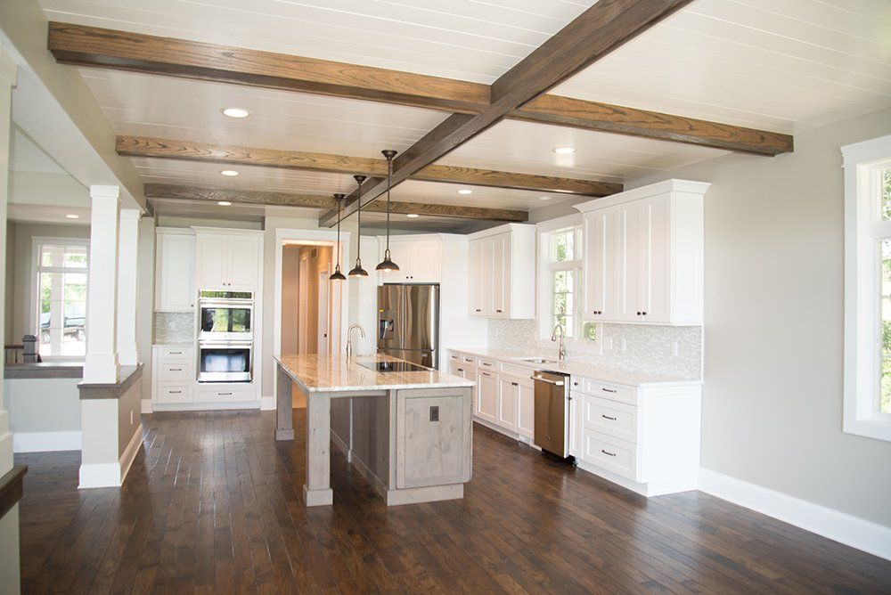 A kitchen with white cabinets and wooden beams on the ceiling.