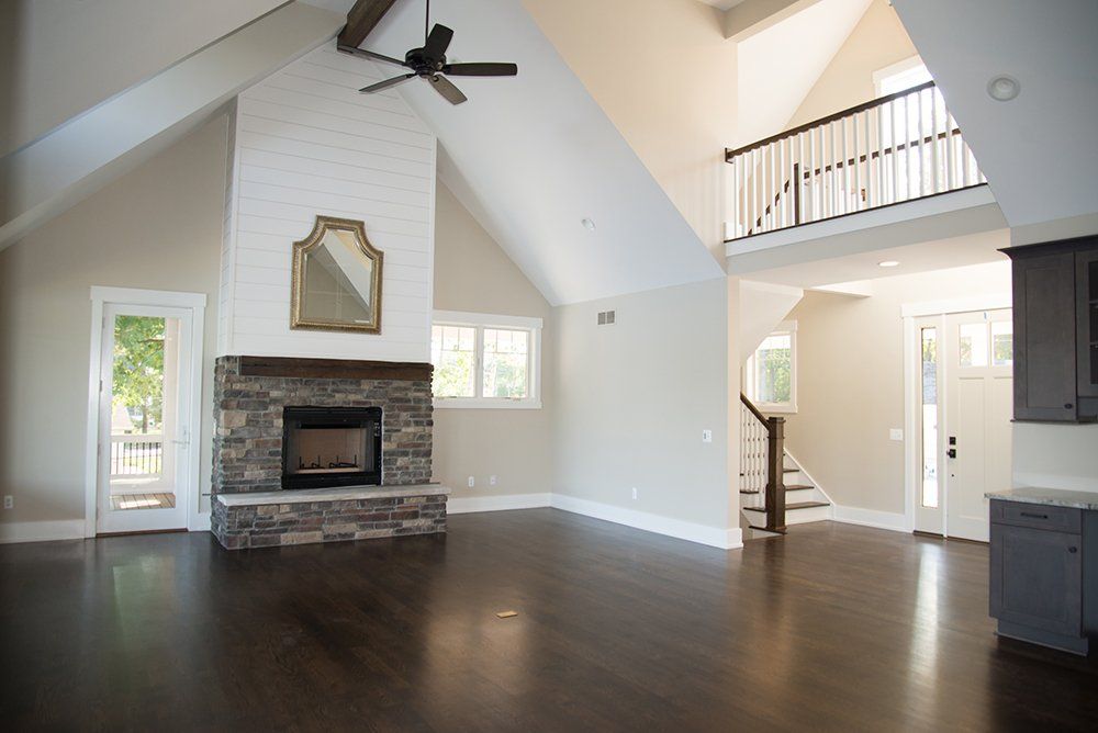 An empty living room with a fireplace and a ceiling fan