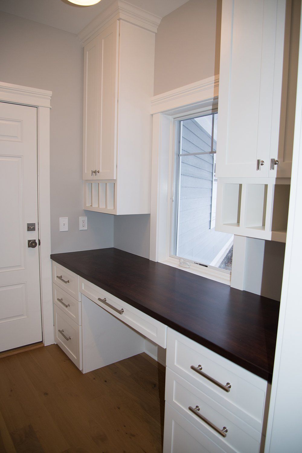 A kitchen with white cabinets and a wooden counter top.
