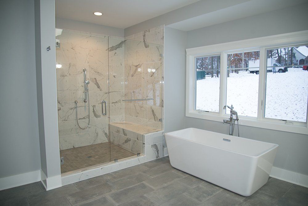 A bathroom with a tub , shower , and window.