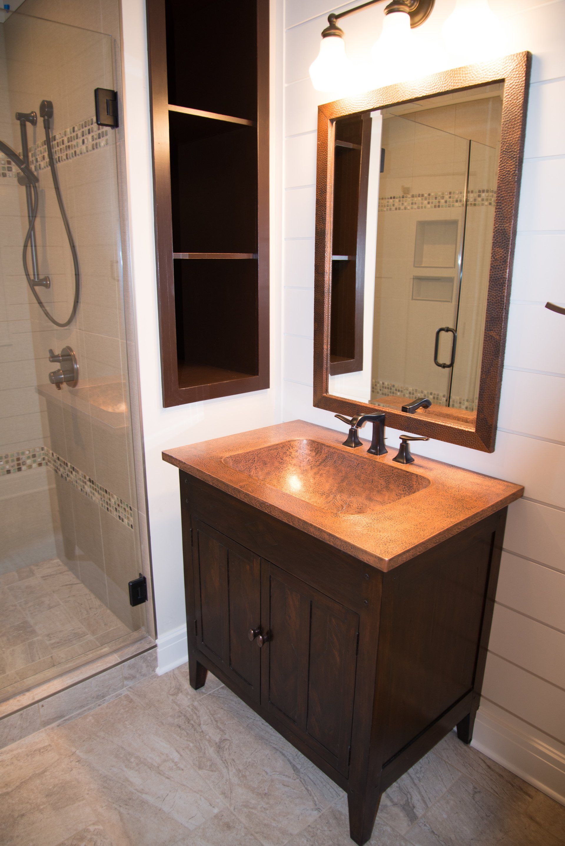 A bathroom with a sink , mirror and shower.