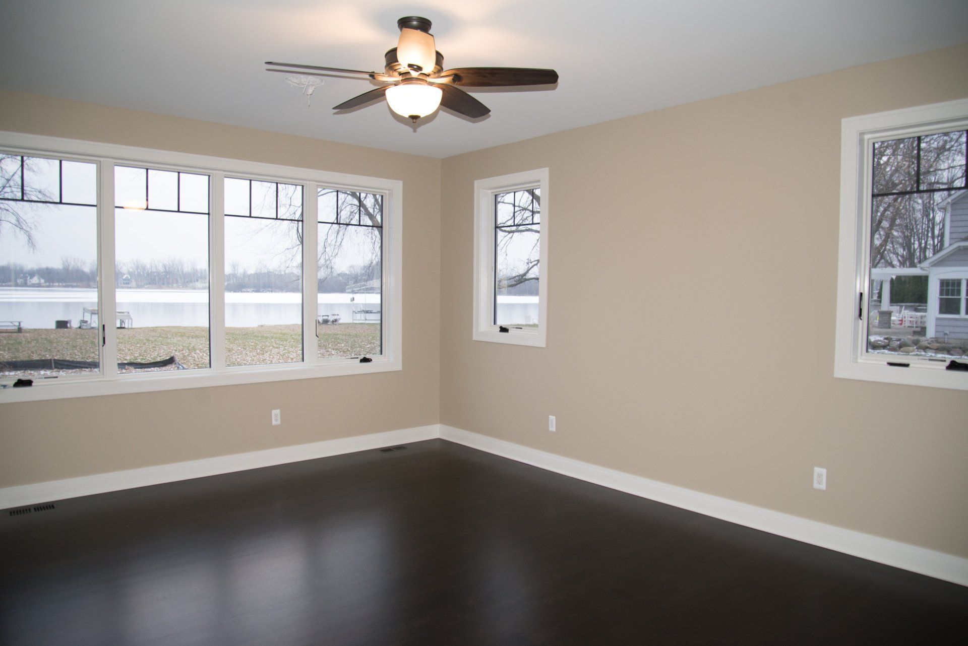 An empty room with a ceiling fan and lots of windows