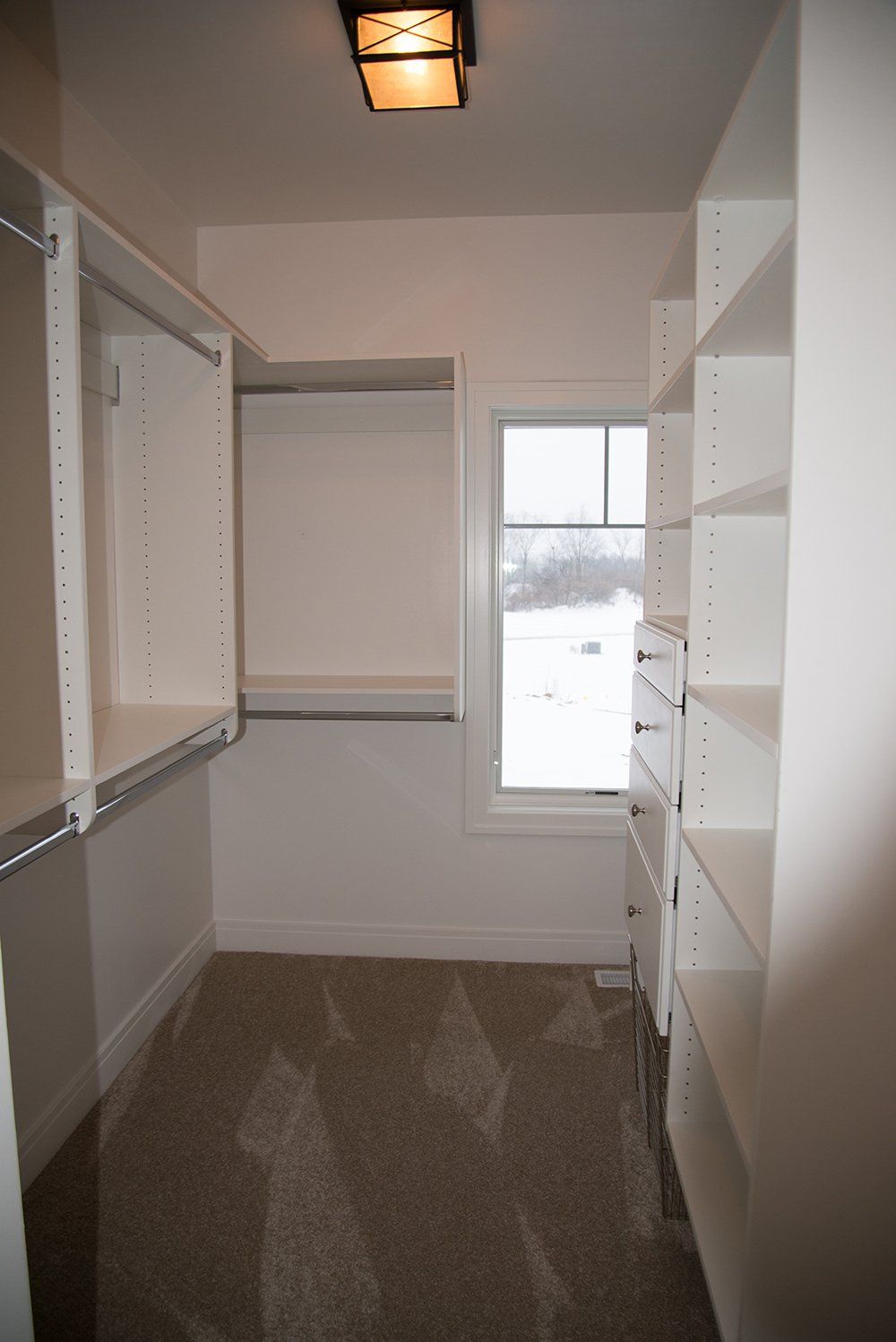 A walk in closet with lots of shelves and a window.