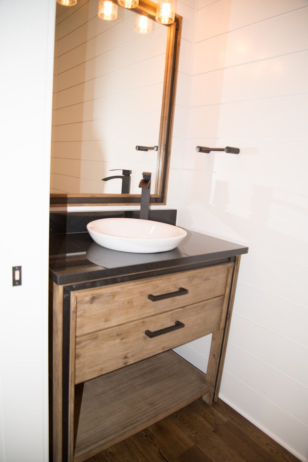 A bathroom with a sink , mirror and drawers.