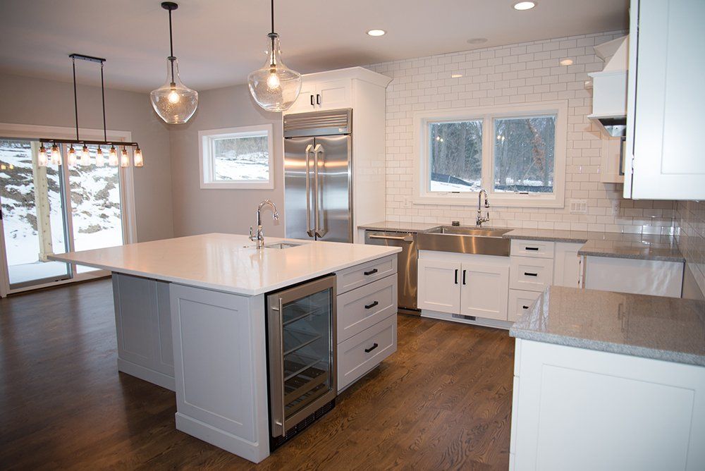 A kitchen with white cabinets and stainless steel appliances and a large island.