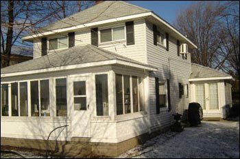 A white house with black shutters and a large porch