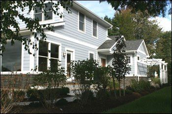 A large house with a lot of windows is surrounded by bushes and trees