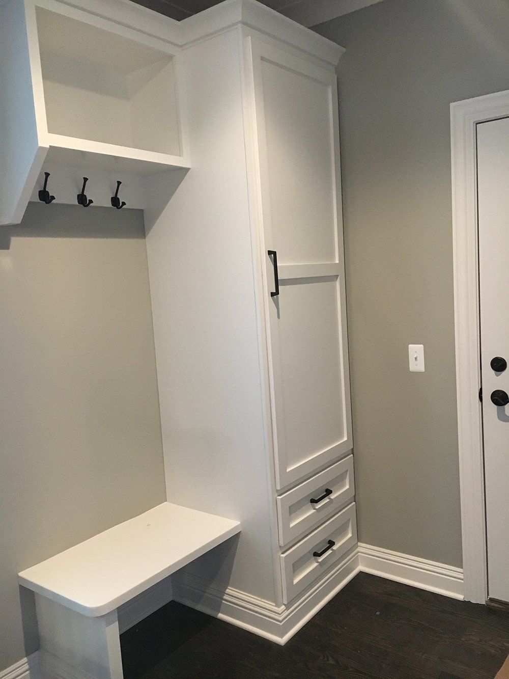 A white cabinet with drawers and a bench in a hallway.