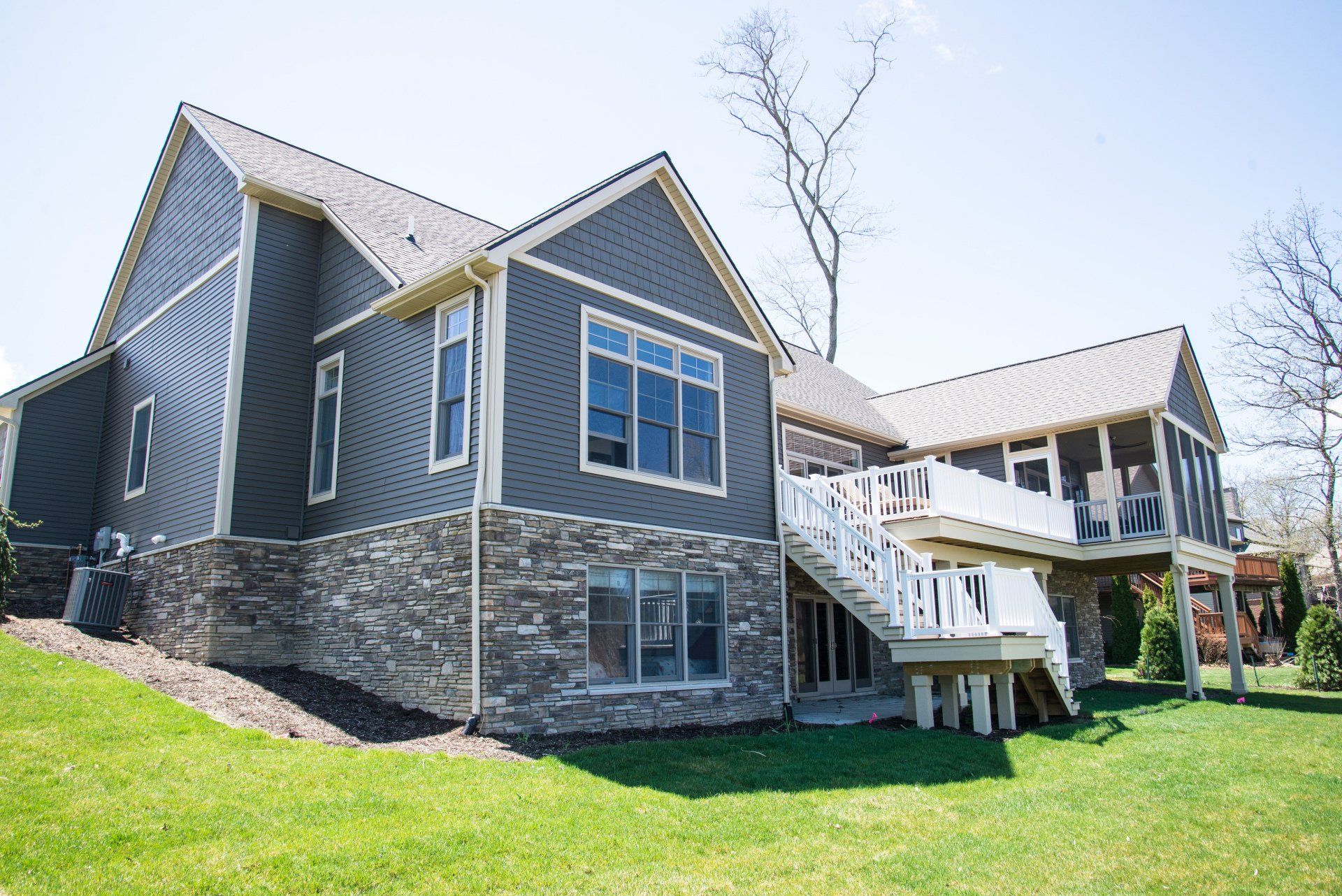 The back of a large house with a large deck and stairs.