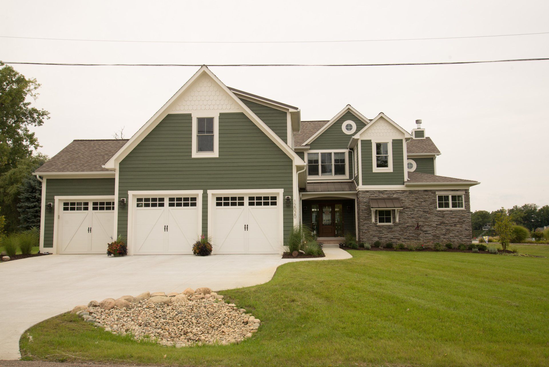 A large house with green siding and white garage doors