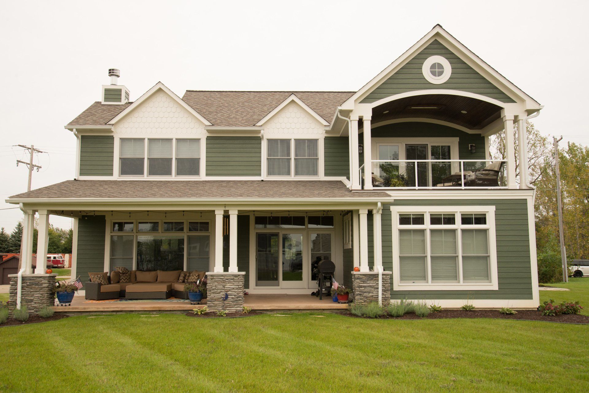 A large green and white house with a large porch.