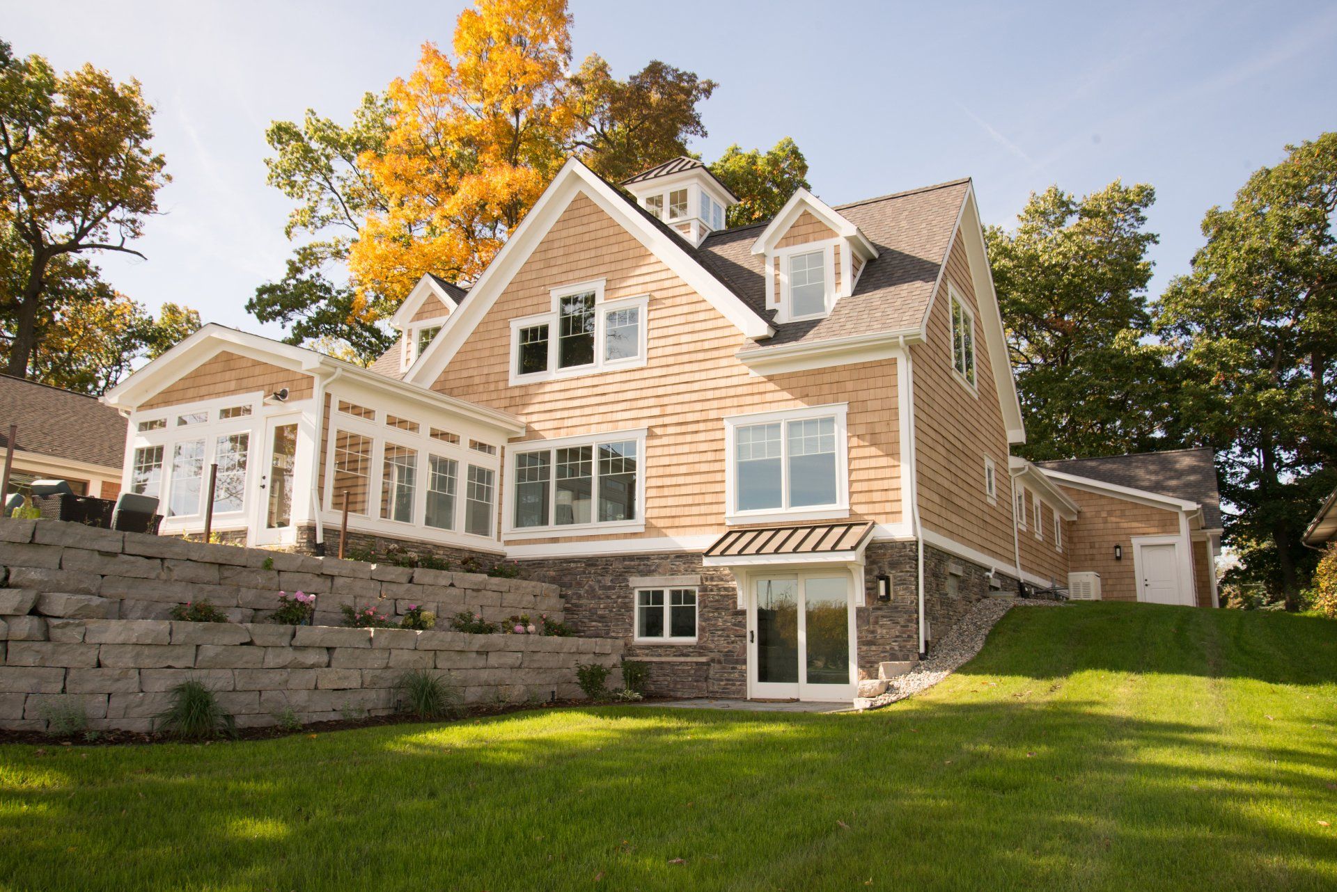 A large house with a lot of windows is sitting on top of a lush green hillside.