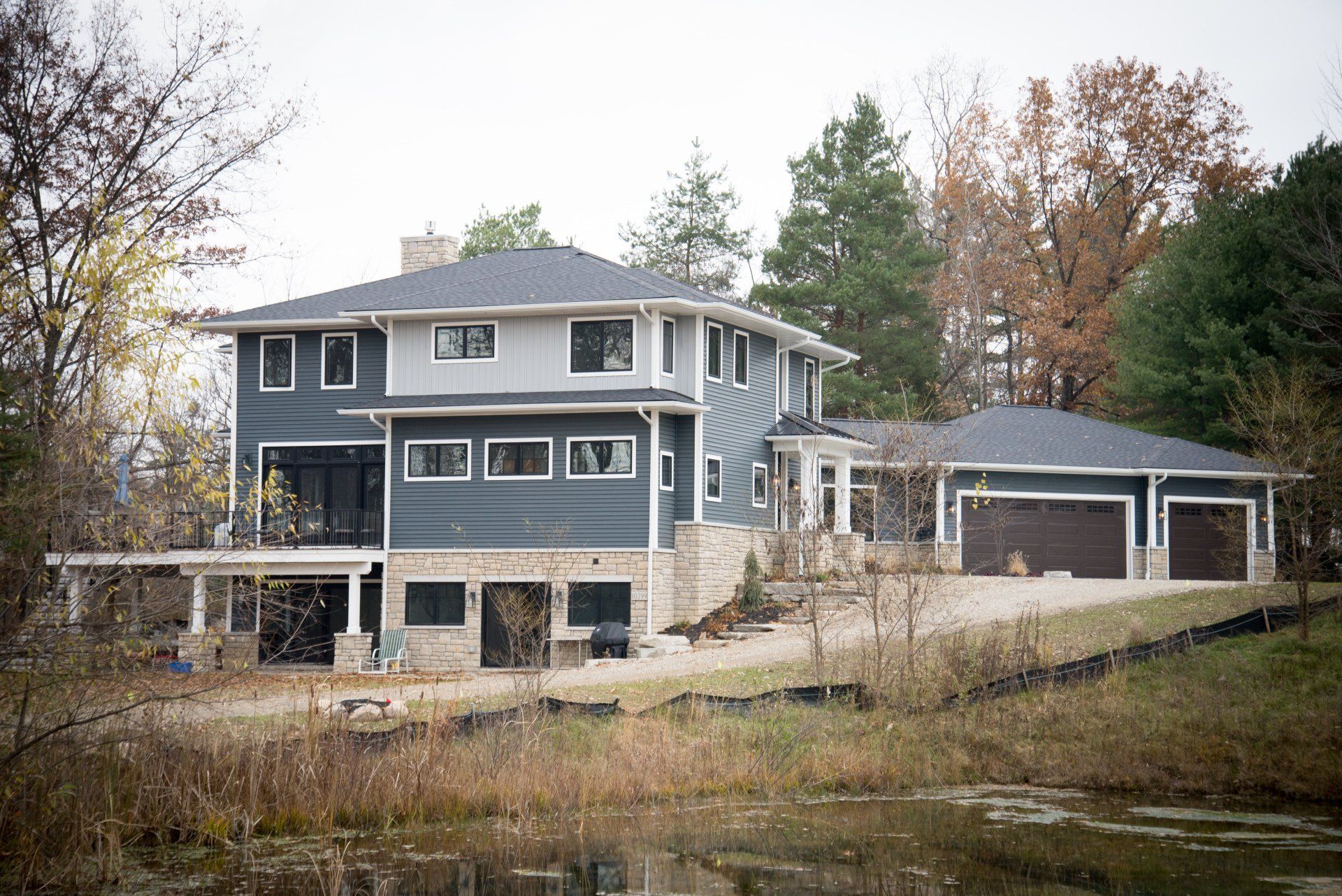 A large house is sitting on top of a hill next to a lake.