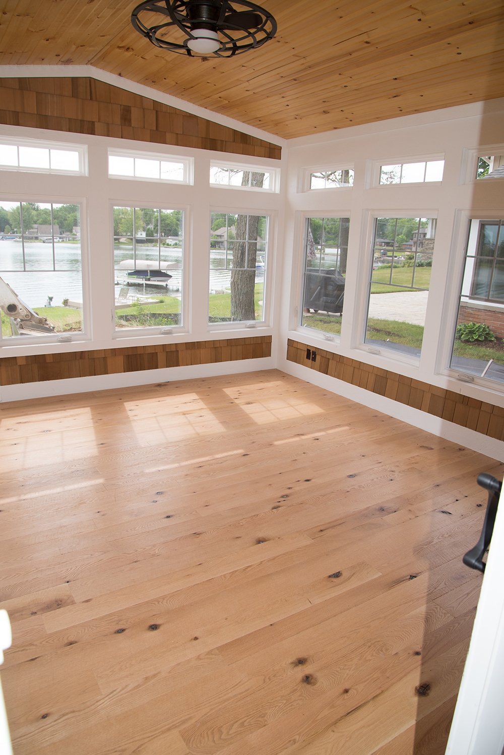 An empty room with wooden floors and a ceiling fan.